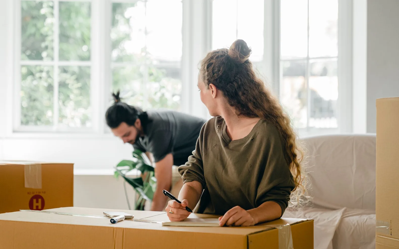 A couple planning a move beside packed boxes in an apartment.