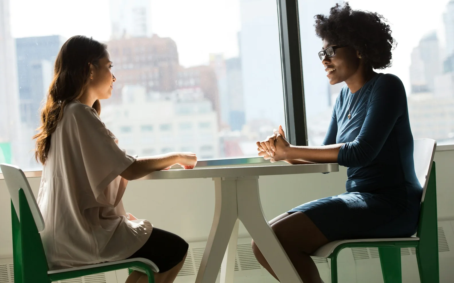 Two colleagues sharing a conversation across a meeting table.