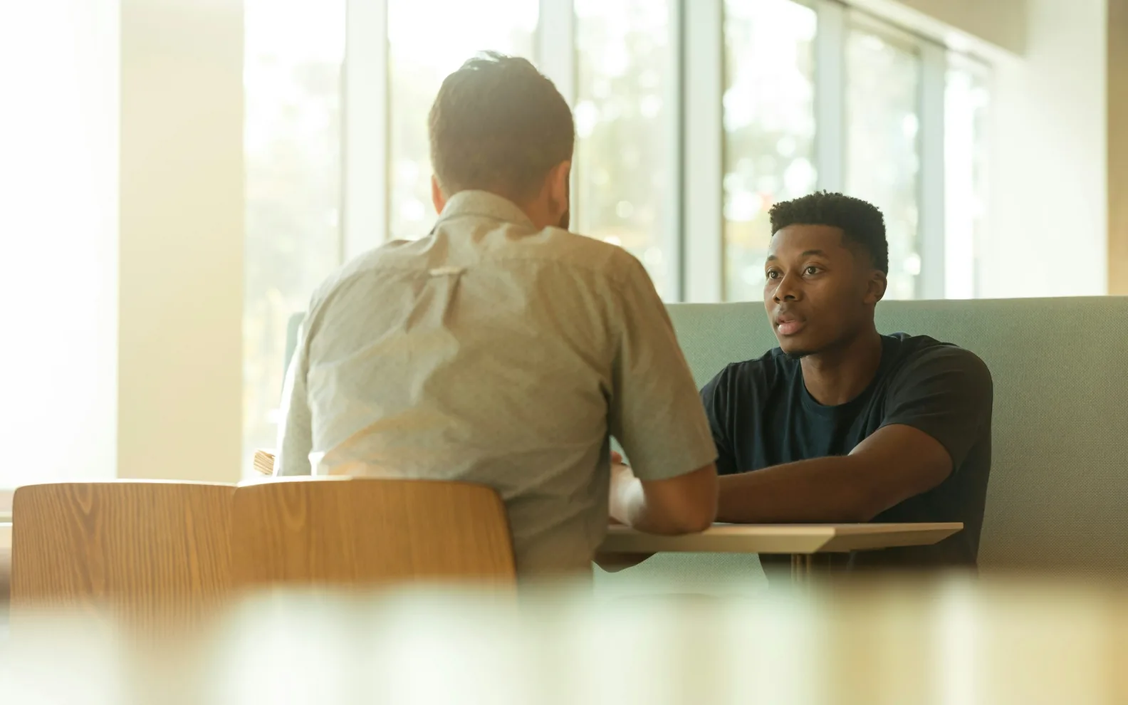 Two colleagues having a conversation in a light office.